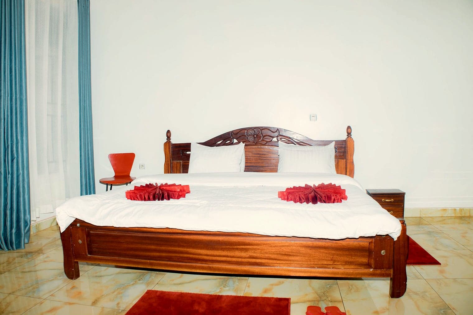 The carved headboard of the Kigali room bed, facing the windows